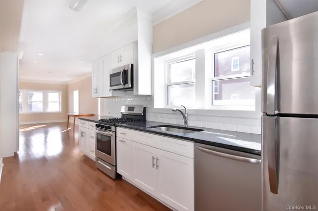 a kitchen with stainless steel appliances granite countertop a refrigerator a sink dishwasher a stove with wooden floors and cabinets