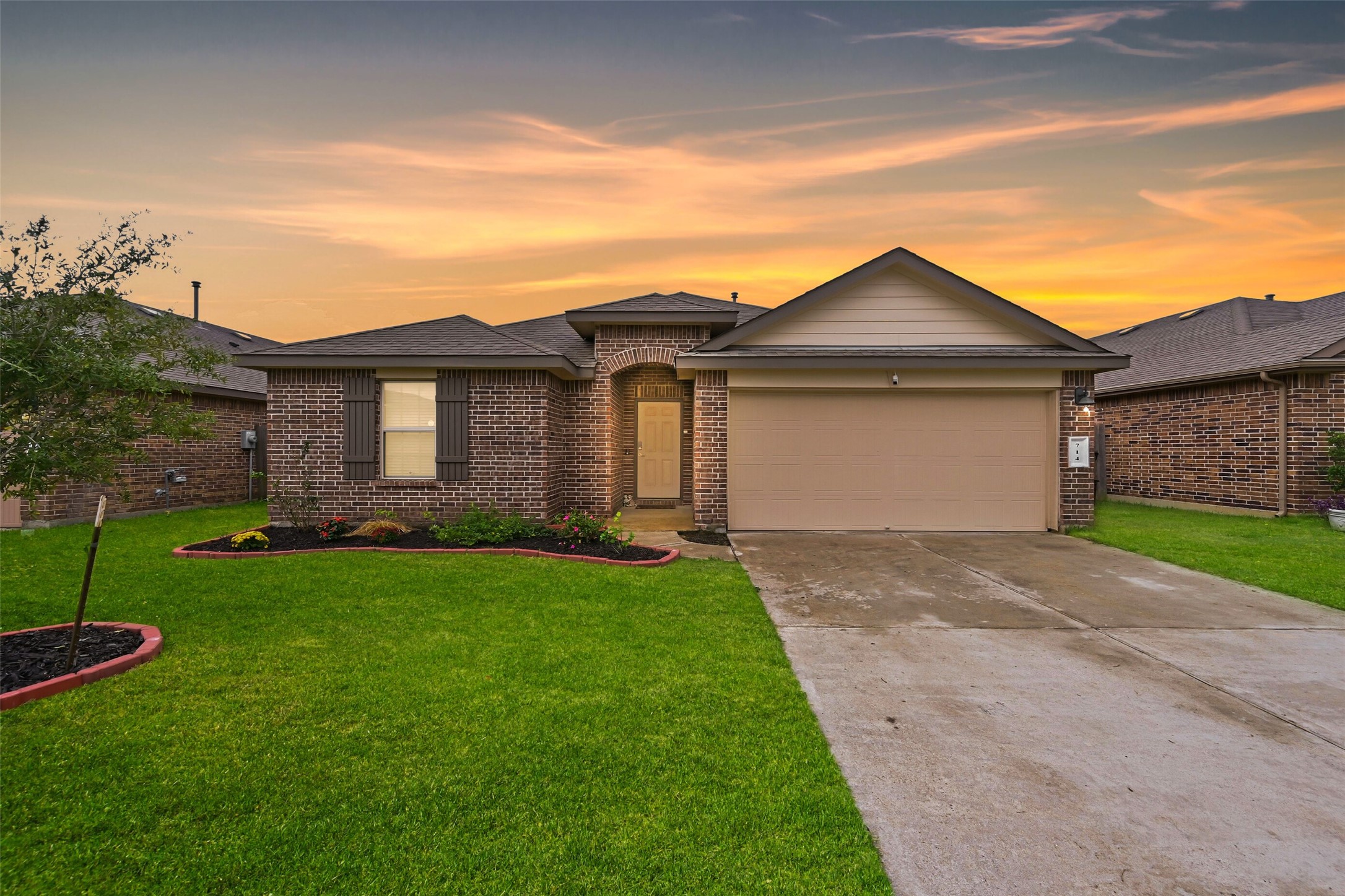 Welcome Home! Featuring a brick façade, landscaped yard, and attached two-car garage.