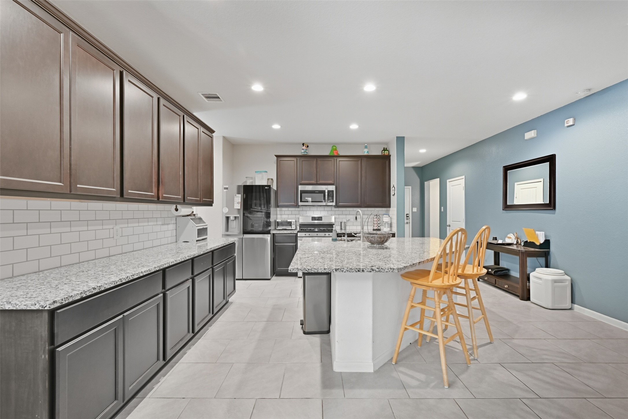 714 Calm Court Rosharon, TX 77583 - Photo 6 of 33 Chef’s kitchen with granite countertops, dark wood cabinetry, stainless steel appliances, and a 5-burner gas range.
