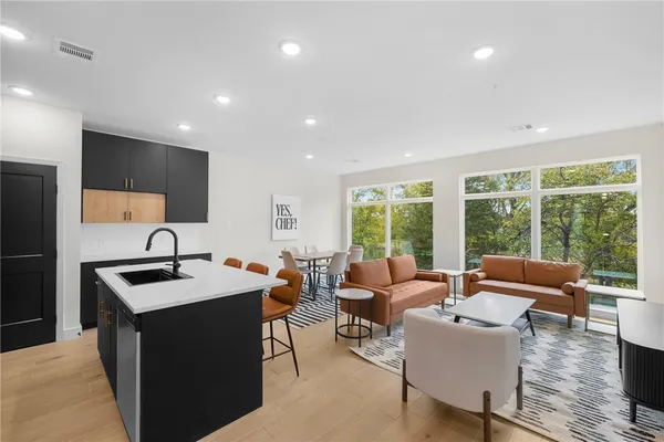 a kitchen with a stove a sink dishwasher a dining table and chairs with wooden floor