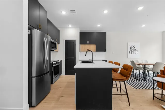 a kitchen with stainless steel appliances kitchen island granite countertop a refrigerator a sink and a microwave