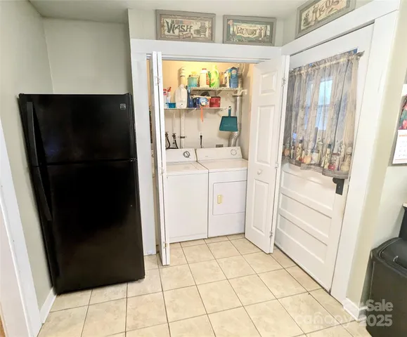 a view of a refrigerator in kitchen and an empty room in wooden floor