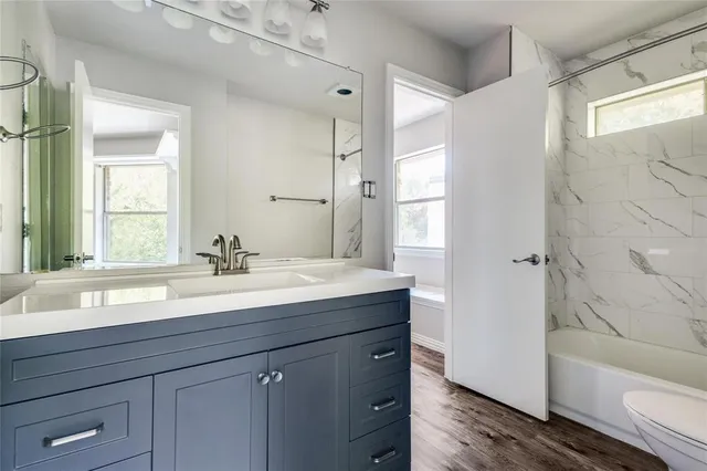 a bathroom with a granite countertop sink mirror and a bathtub