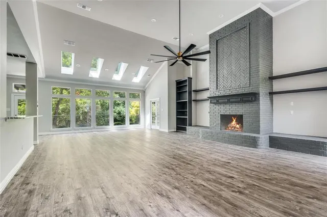 a view of an empty room with a window and kitchen view