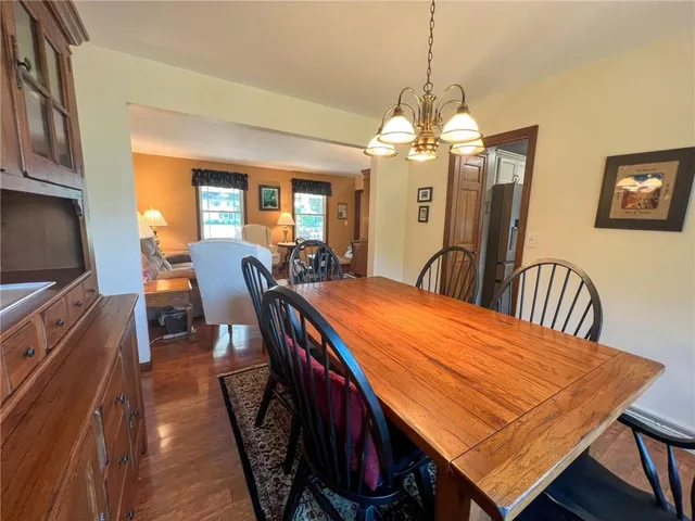 a dining room with wooden floor a chandelier a wooden table and chairs