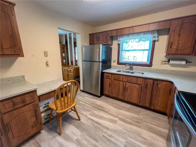 a kitchen with stainless steel appliances granite countertop a refrigerator sink and wooden cabinets