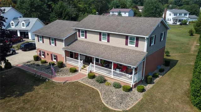 an aerial view of a house with swimming pool and trees in the background
