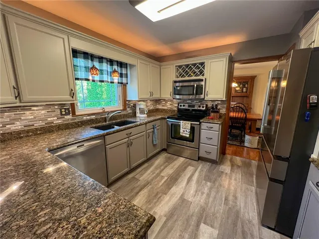 a kitchen with stainless steel appliances granite countertop a stove a sink and a refrigerator