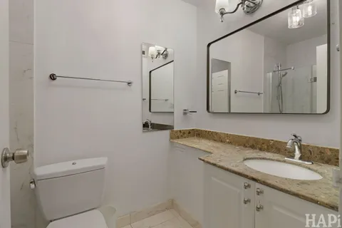 a bathroom with a granite countertop sink toilet and mirror