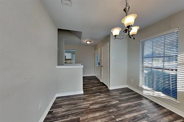 a view of a hallway with wooden floor and a chandelier