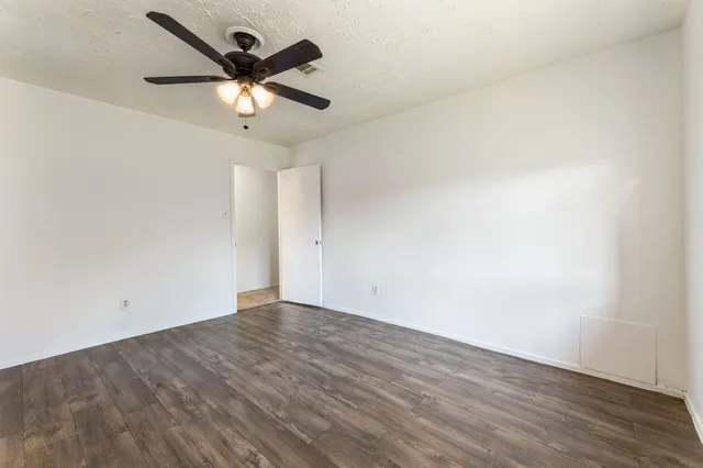 an empty room with wooden floor and ceiling fan