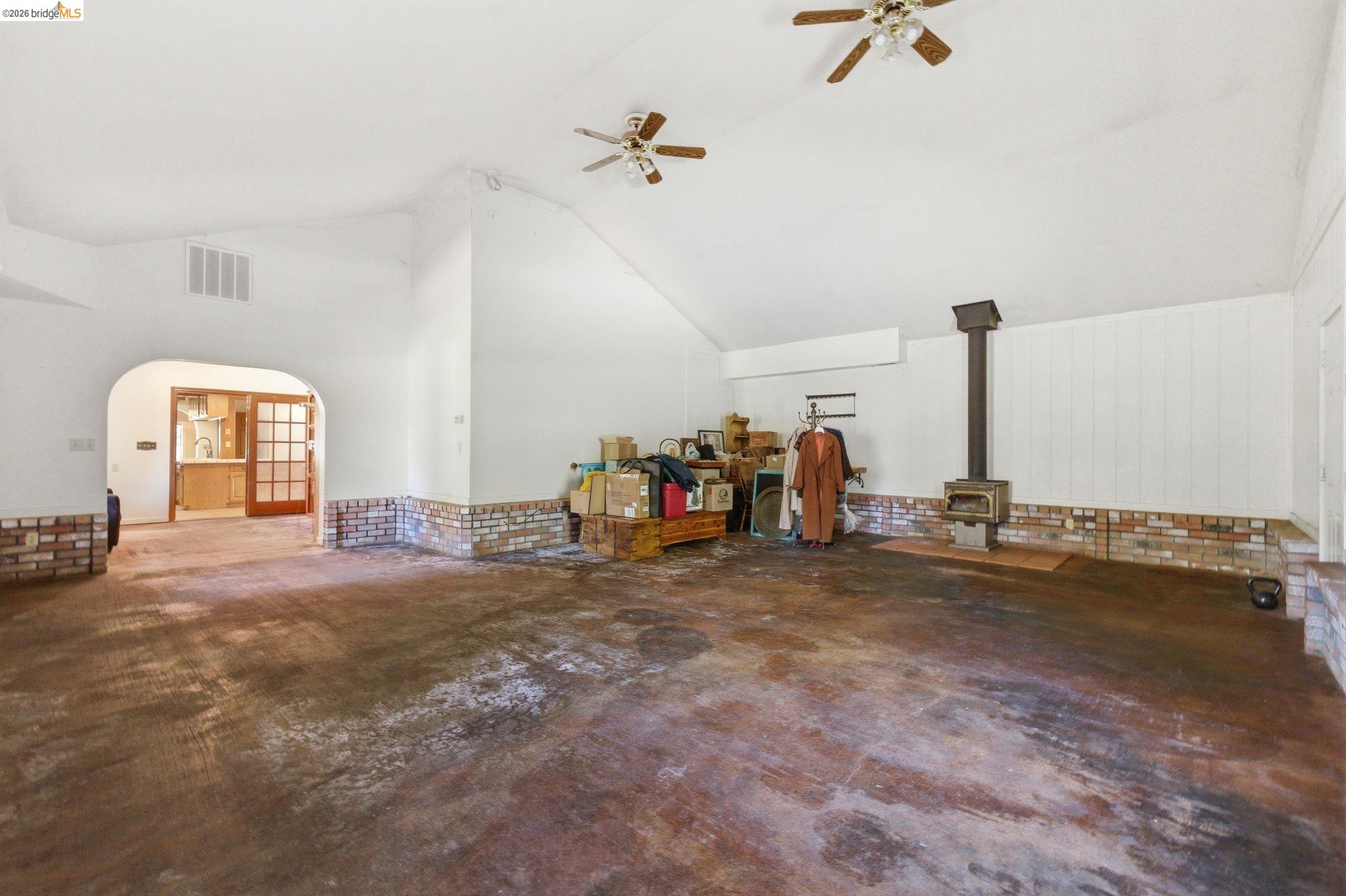23608 Porcina Way Columbia, CA 95310 - Photo 23 of 51 Bonus room featuring arched walkways, a ceiling fan, lofted ceiling, a wood stove, and concrete flooring