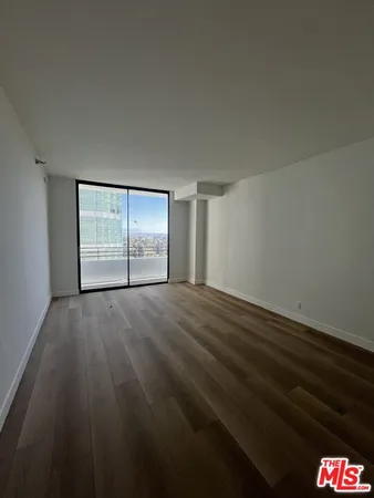 a view of an empty room with wooden floor and cabinet