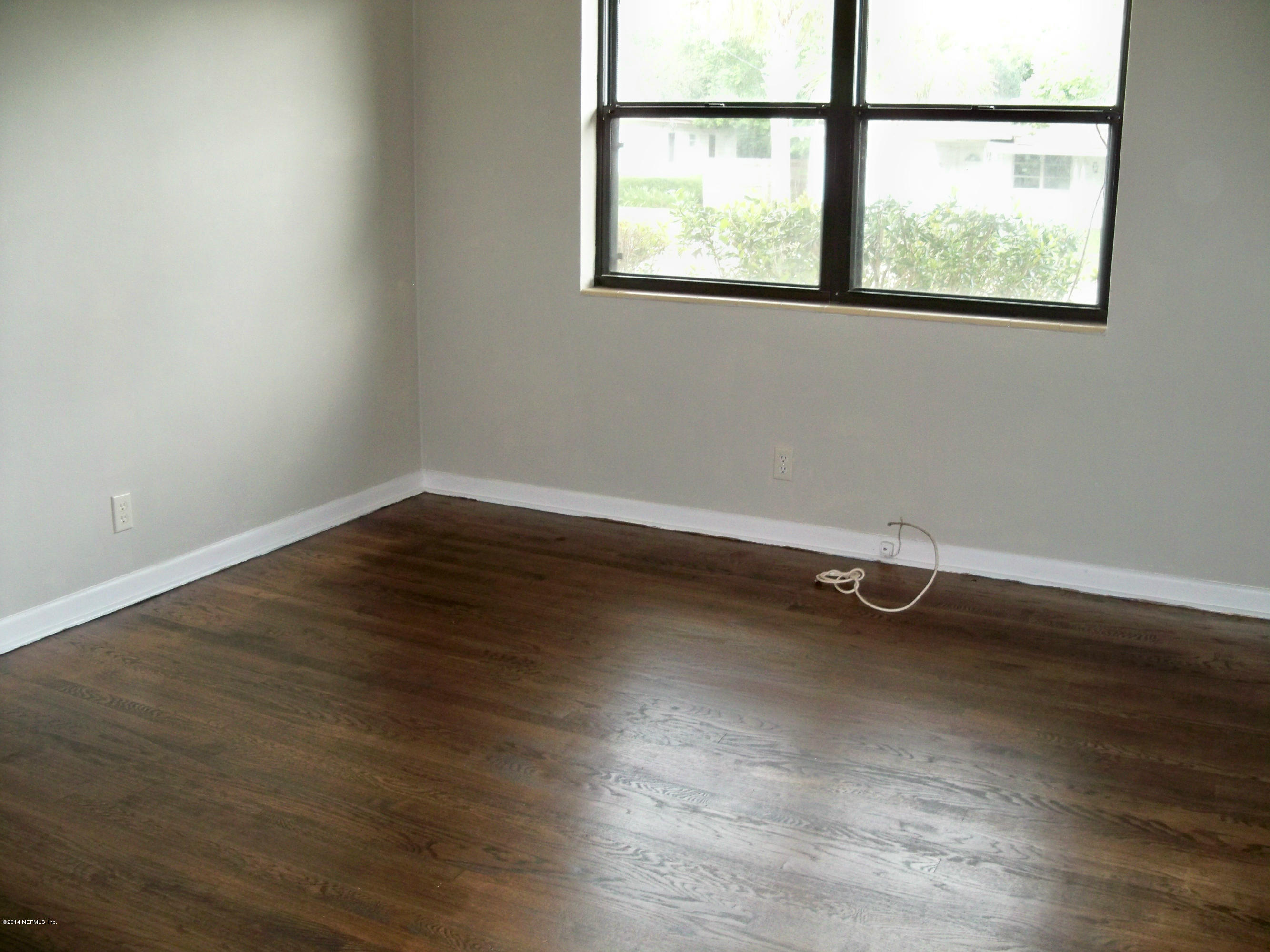 3219 Rogero Road Jacksonville, FL 32277 - Photo 11 of 13 an empty room with wooden floor and windows