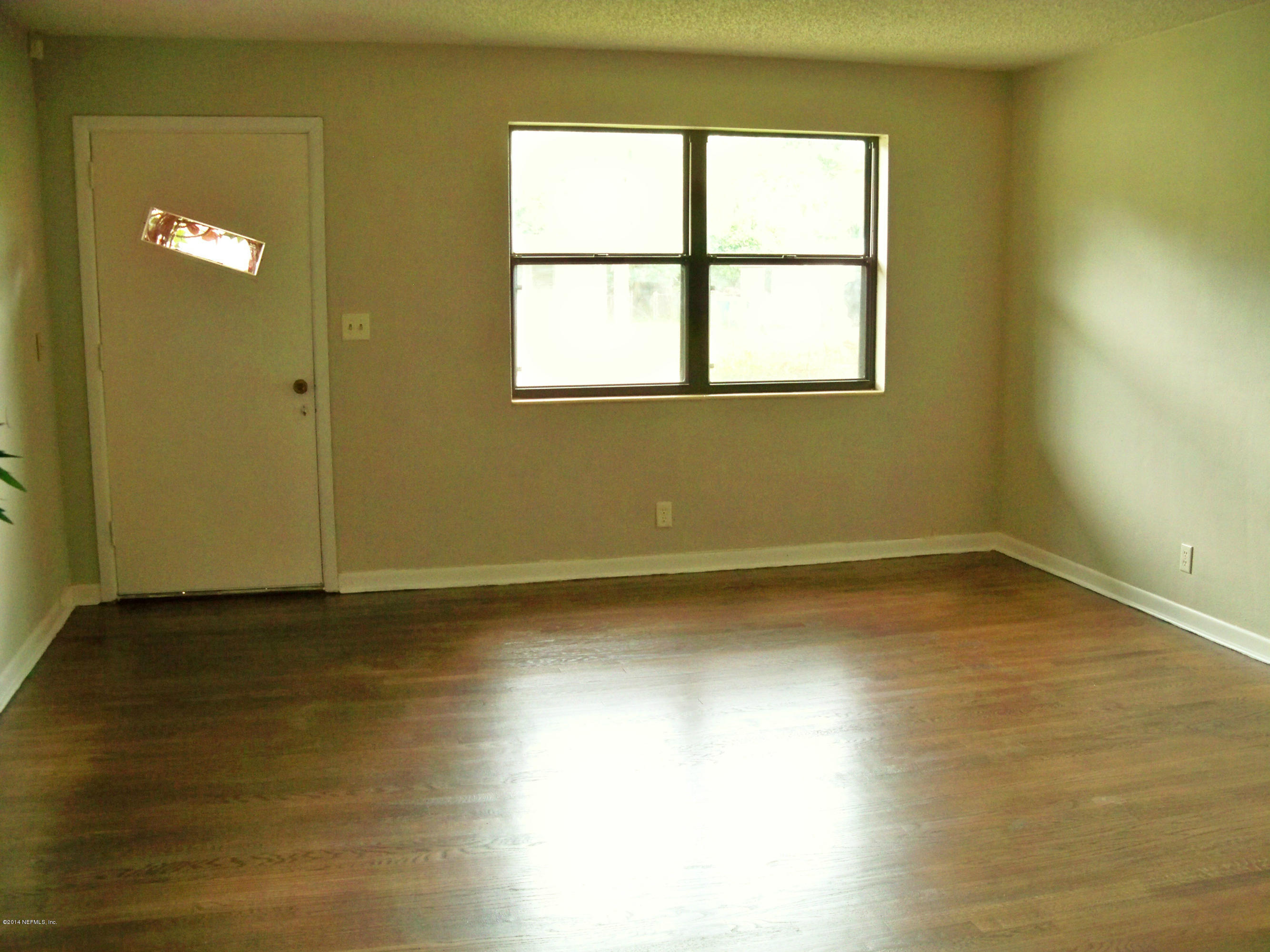 3219 Rogero Road Jacksonville, FL 32277 - Photo 3 of 13 a view of an empty room with wooden floor and a window