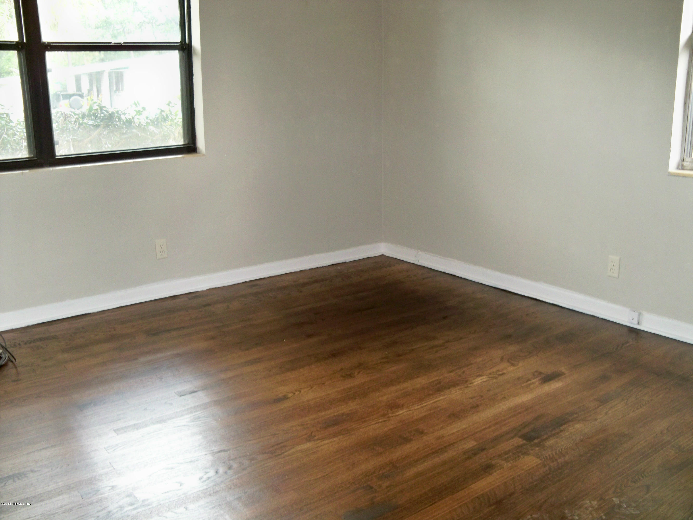 3219 Rogero Road Jacksonville, FL 32277 - Photo 8 of 13 an empty room with wooden floor and windows