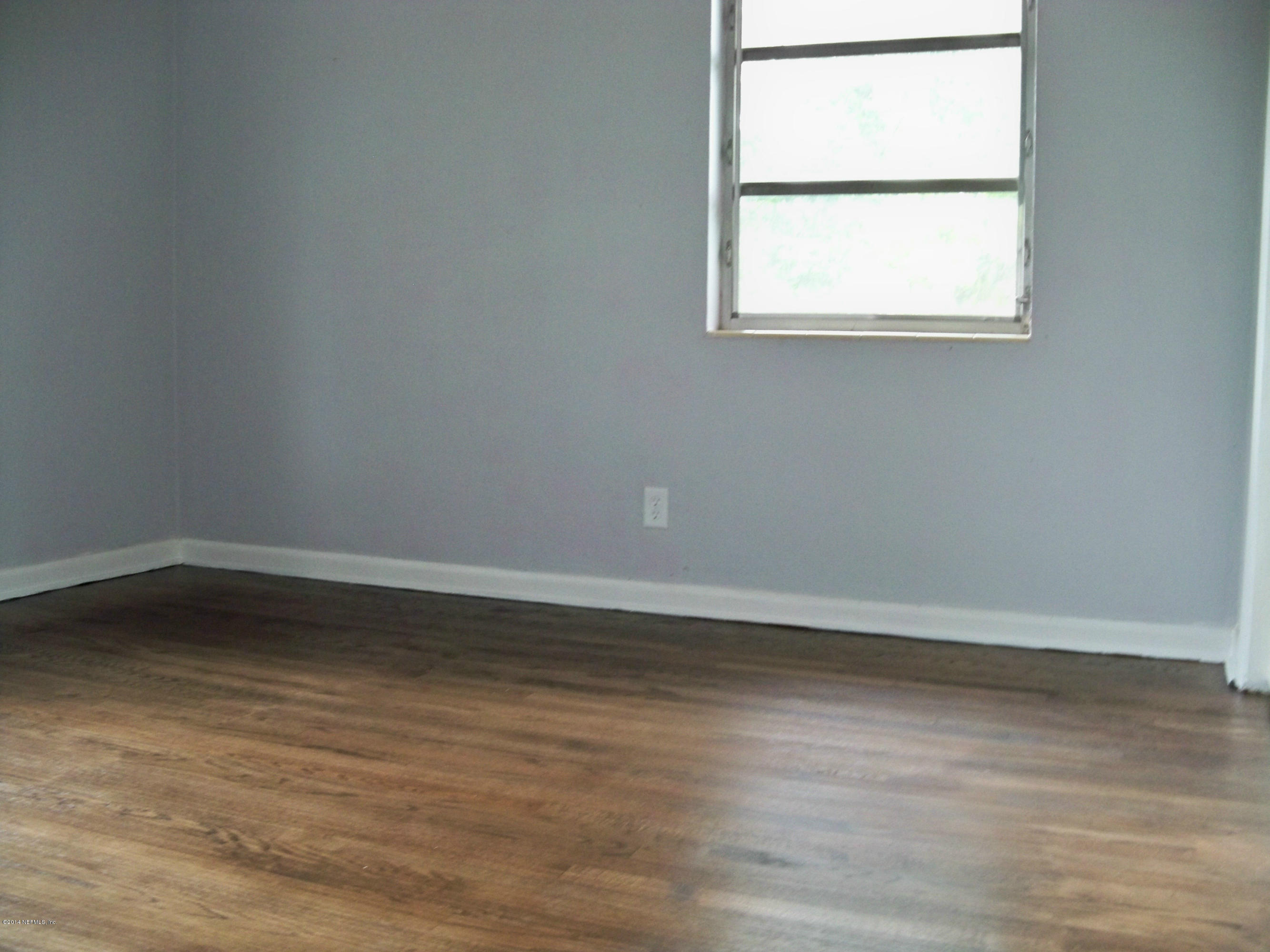 3219 Rogero Road Jacksonville, FL 32277 - Photo 9 of 13 an empty room with wooden floor and windows
