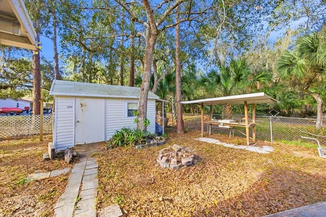 a view of a backyard with wooden fence and large trees