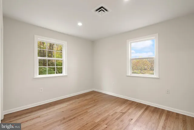 an empty room with windows and a ceiling fan