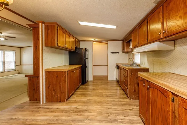 a kitchen with stainless steel appliances granite countertop a refrigerator a sink dishwasher and a stove with wooden cabinets