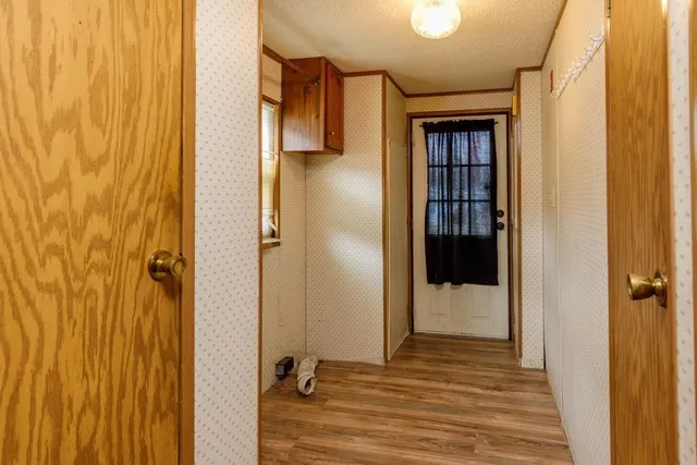 a view of a hallway with wooden floor and a bathroom
