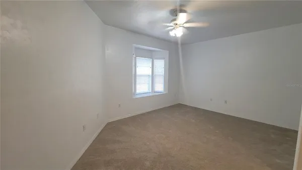 an empty room with a window and a fan