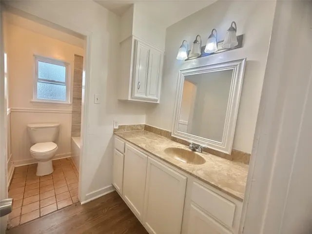 a bathroom with a granite countertop sink and a toilet