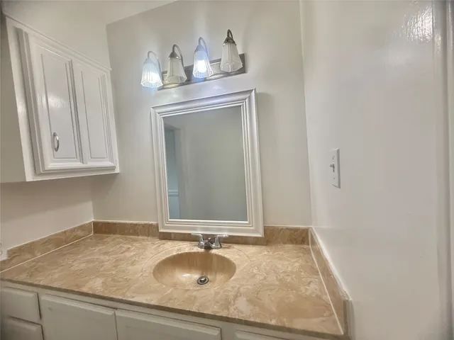 a bathroom with a granite countertop sink and a mirror
