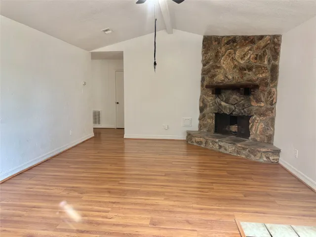 a view of a livingroom with wooden floor and a fireplace