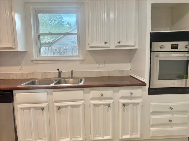 a kitchen with white cabinets and sink