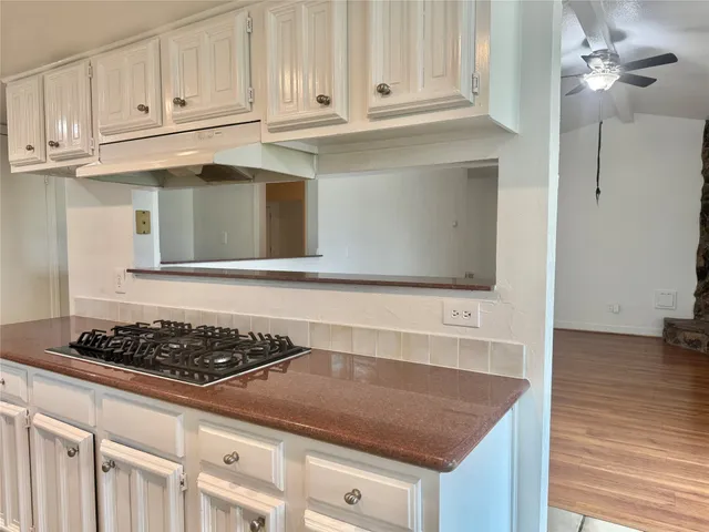 a kitchen with granite countertop white cabinets and stainless steel appliances