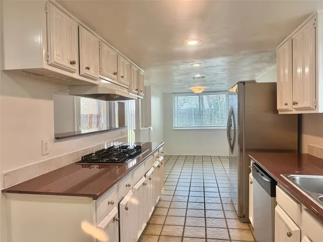 a kitchen with granite countertop a stove a sink and a refrigerator