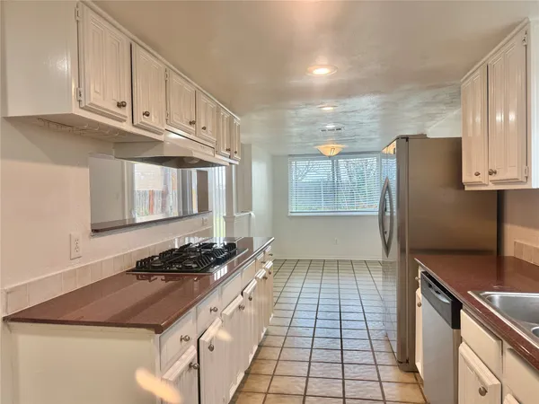 a kitchen with granite countertop a stove a sink and a refrigerator