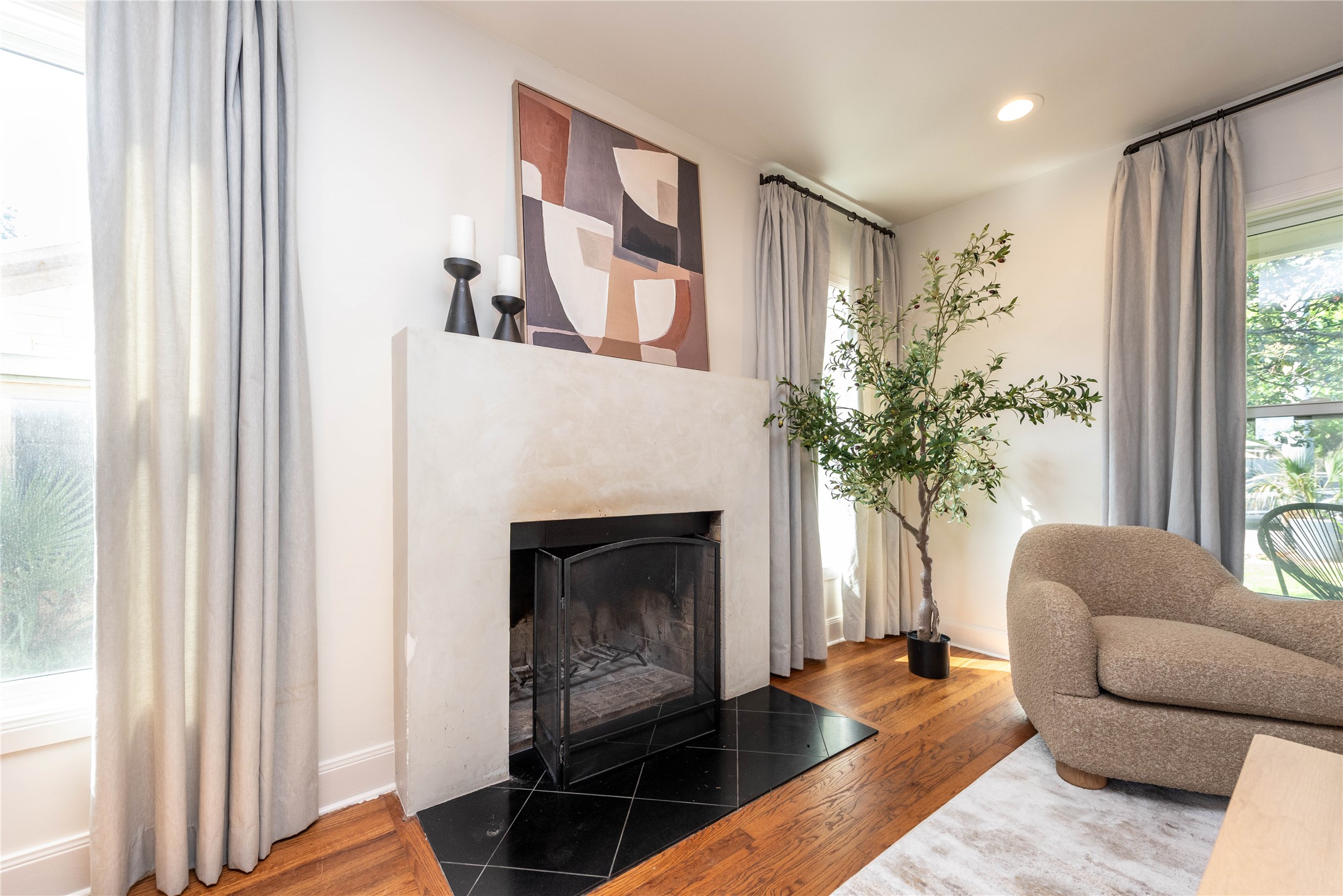 503 East 46th Street Austin, TX 78751 - Photo 6 of 25 Fireplace featuring a smooth plaster finish, black tile hearth, and a black fire screen