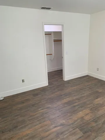 a view of an empty room with wooden floor and closet