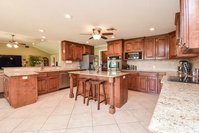 a kitchen with stainless steel appliances kitchen island granite countertop a sink a counter top space and cabinets