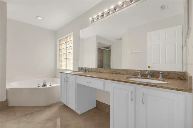 a bathroom with a granite countertop bathtub a double vanity sink and a mirror
