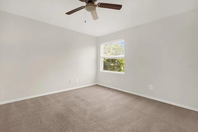an empty room with a window and a fan