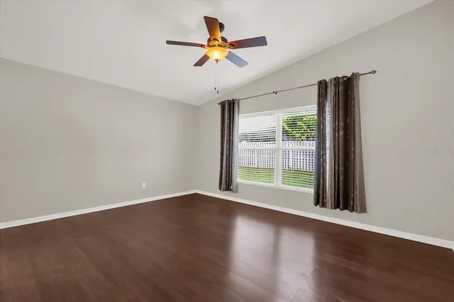 a view of room with wooden floor and a ceiling fan