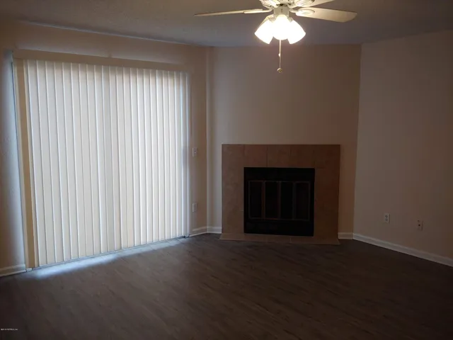 an empty room with wooden floor windows and a chandelier fan
