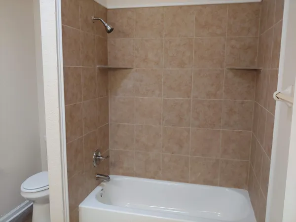 a bath tub sitting next to a white toilet and a shower