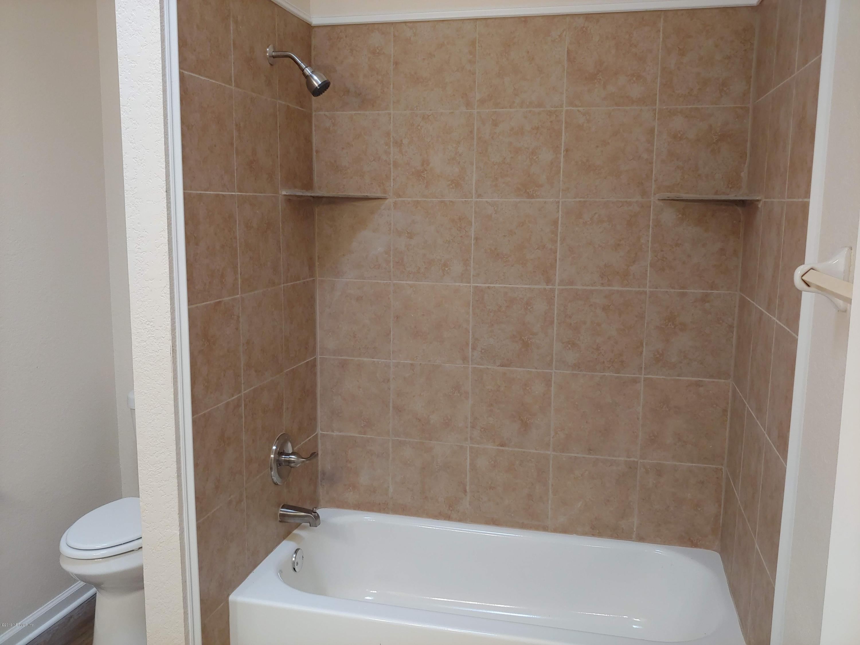 791 Assisi Lane, Unit 303 Jacksonville, FL 32233 - Photo 21 of 35 a bath tub sitting next to a white toilet and a shower
