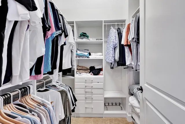 a view of walk in closet with clothes and shoes