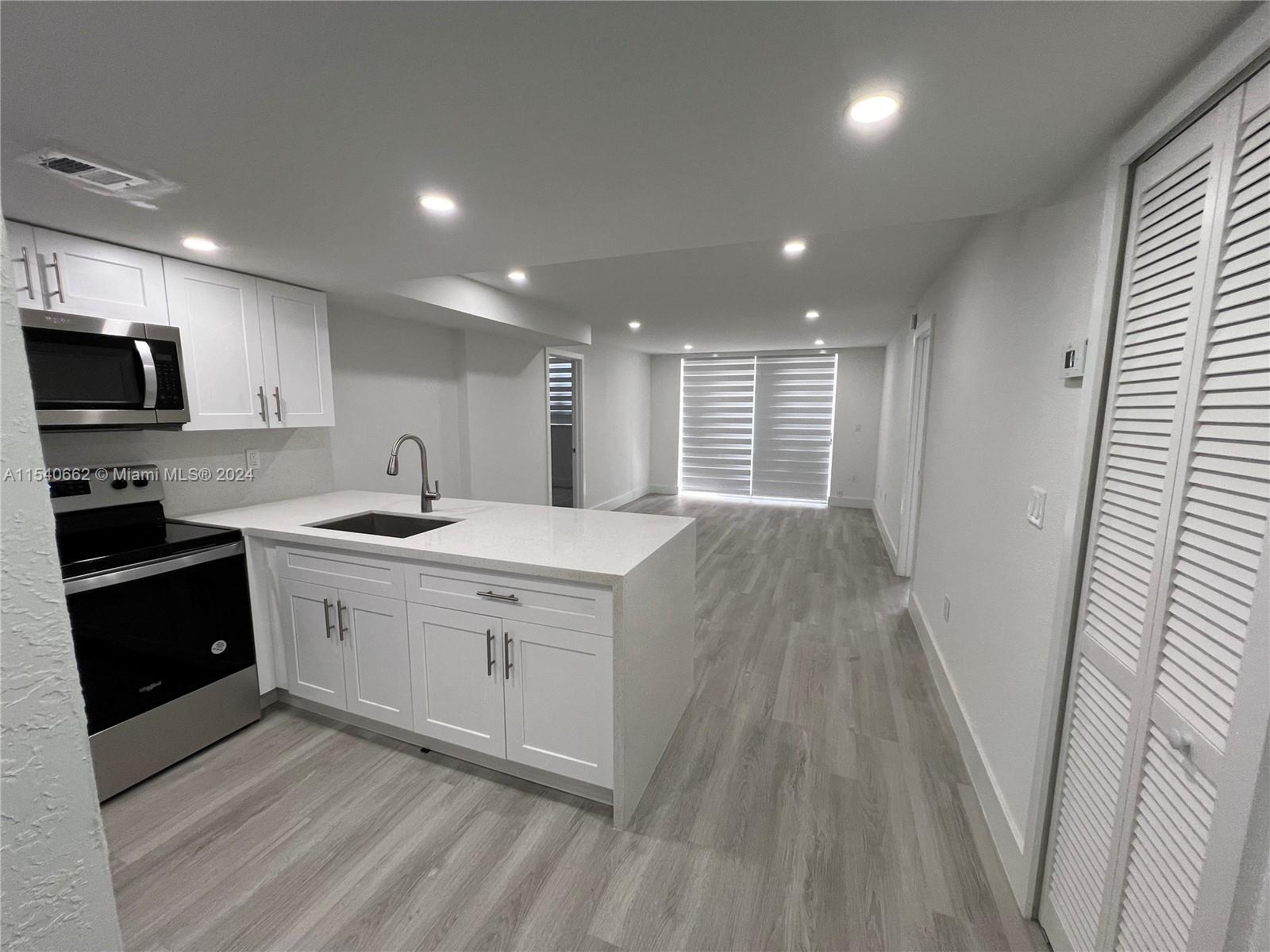 a kitchen with granite countertop a sink a counter space cabinets and stainless steel appliances