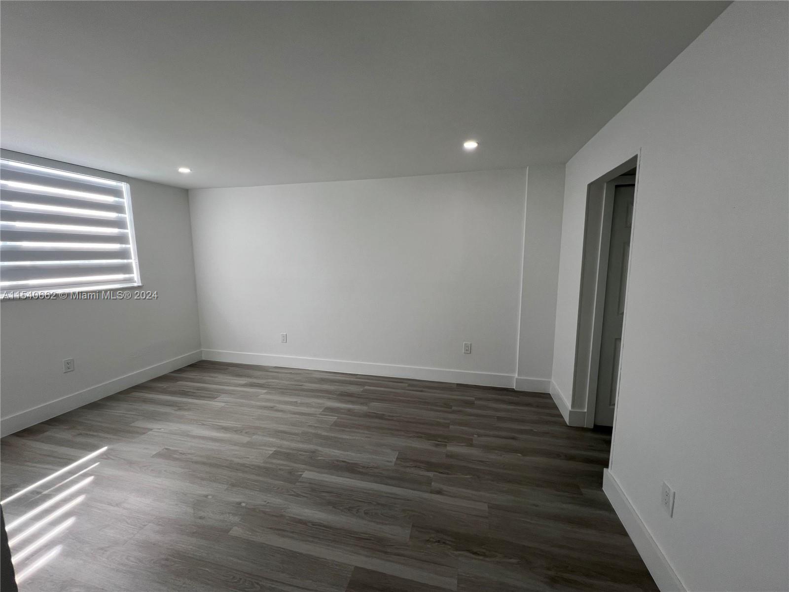 14155 Southwest 87th Street, Unit E108 Miami, FL 33183 - Photo 4 of 9 an empty room with wooden floor and windows