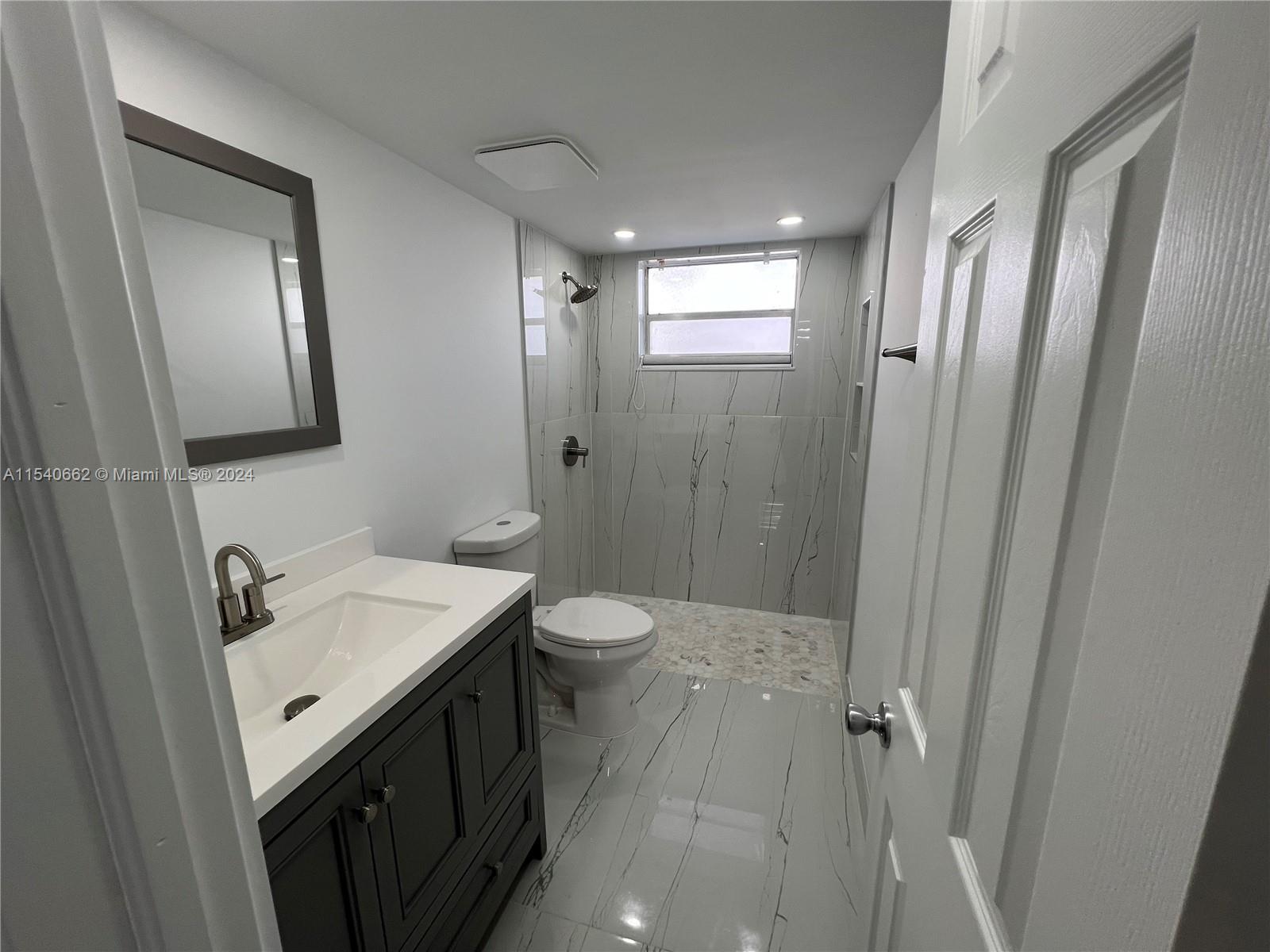 14155 Southwest 87th Street, Unit E108 Miami, FL 33183 - Photo 5 of 9 a bathroom with a sink a toilet and shower