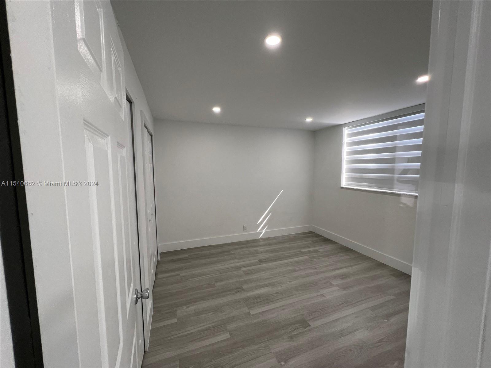 14155 Southwest 87th Street, Unit E108 Miami, FL 33183 - Photo 6 of 9 an empty room with wooden floor and windows