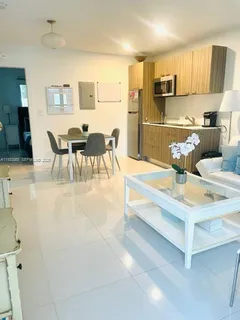 a living room with stainless steel appliances furniture a flat screen tv and kitchen view