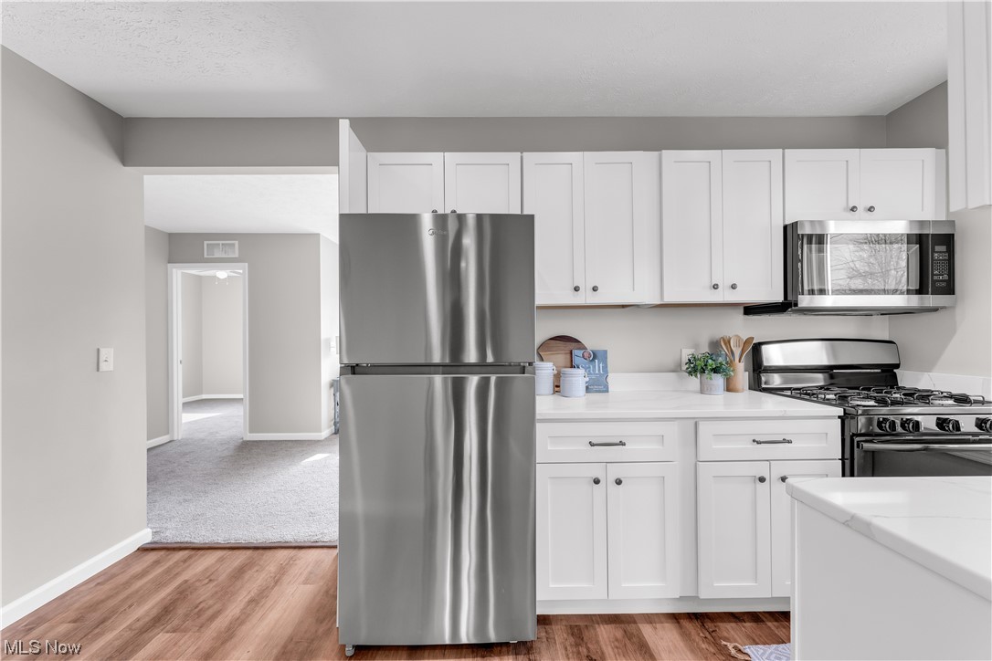 7501 Southland Road Mentor, OH 44060 - Photo 15 of 21 Kitchen with light hardwood / wood-style floors, appliances with stainless steel finishes, and white cabinets