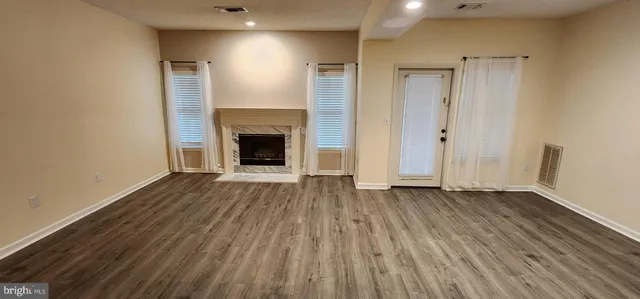 an empty room with wooden floor and a fireplace